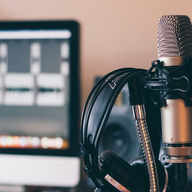 A broadcast microphone beside a studio screen